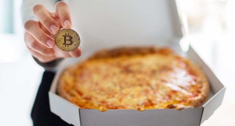 Pizza em uma mão moeda de bitcoin na outra