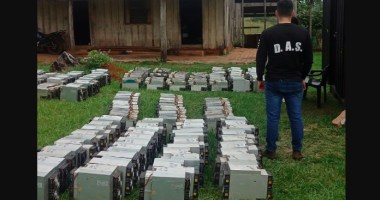 Agente da Polícia nacional do Paraguai observando centenas de máquinas de mineração em gramado