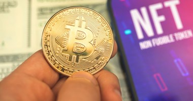 moeda de bitcoin ao lado de tela com sigla NFT