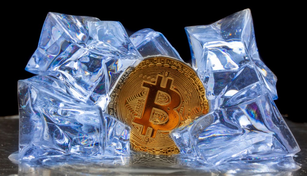 Moeda de Bitcoin envolta a pedras de gelo