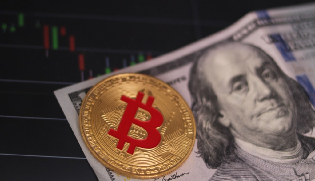 Moeda de Bitcoin sobre nota de dólar