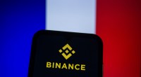 celular com logotipo da Binance e uma bandeira da França ao fundo