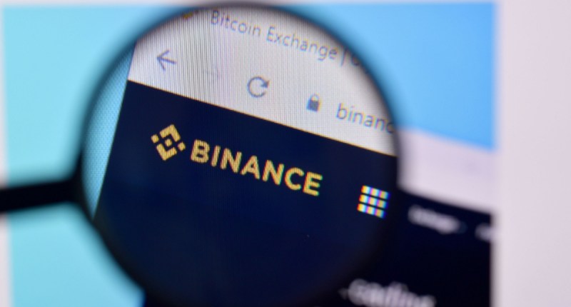 Tela de computador com logotipo da Binance e lente de aumento