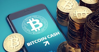 Moedas do Bitcoin Cash (BCH) ao lado de um celular com o logo do projeto