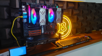 Equipamento de mineração com CPU em uma mesa de escritório com sinal luminoso do Bitcoin atrás