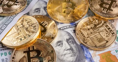 mescla de dólares e moedas de bitcoin sobre a mesa