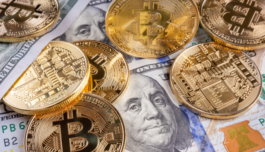 mescla de dólares e moedas de bitcoin sobre a mesa