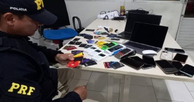 Agente da Polícia Rodoviária Federal (PRF) posa ao lado de dispositivos eletrônicos apreendidos