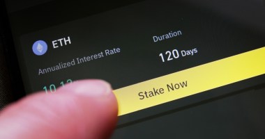 dedo sobre tela de celular em serviço de staking de criptomoeda