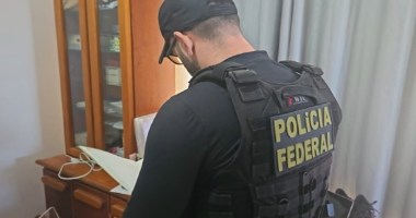 Agente da Polícia Federal dentro de residência fazendo anotações