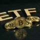 Moedas de bitcoin sob mesa escura com sigal ETF