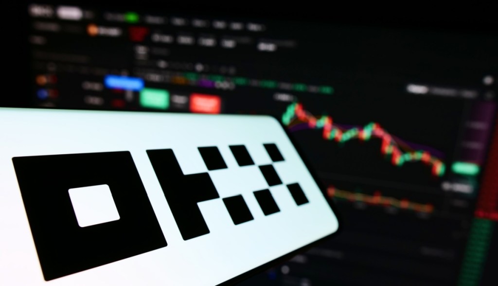Logotipo OKX ao fundo tela trading