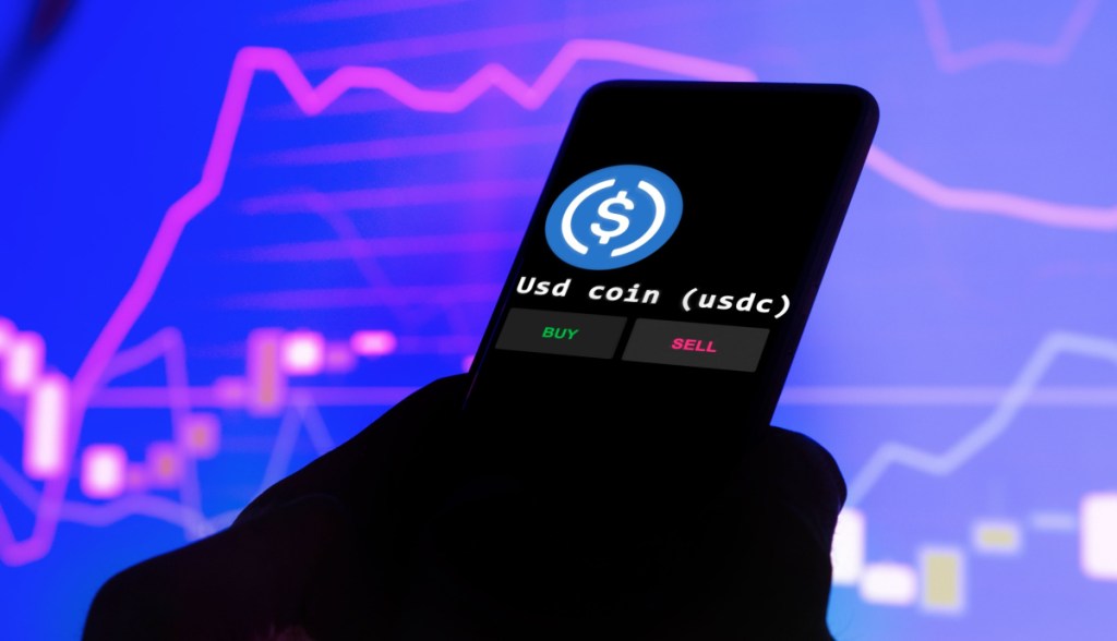 celular com logo da circle usd coin USDC com grafico ao fundo