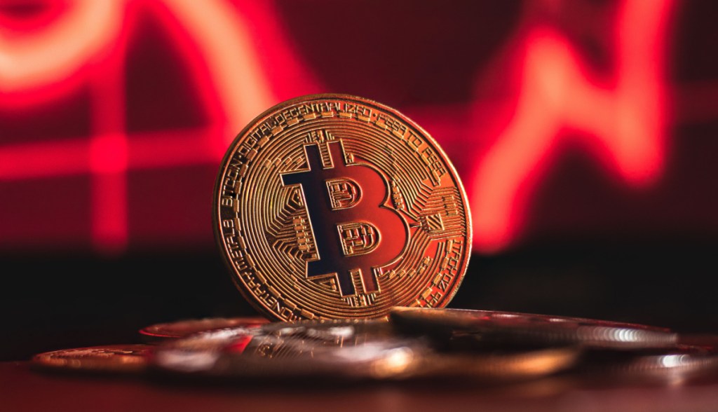 moeda de bitcoin e grafico vermelho de queda no fundo