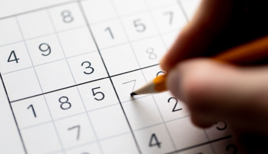 uma pessoa preenchendo um Sudoku