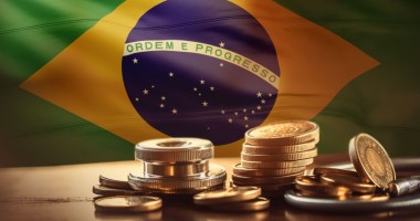 Moedas douradas à frente de bandeira do Brasil