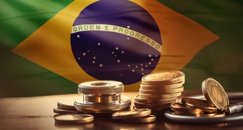 Moedas douradas à frente de bandeira do Brasil