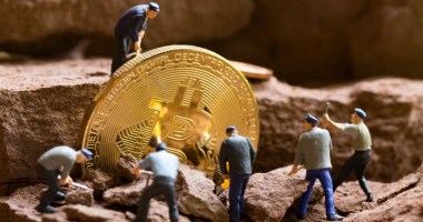 homens em miniaturas lidando com moeda gigante de bitcoin