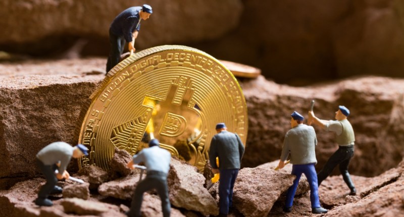 homens em miniaturas lidando com moeda gigante de bitcoin