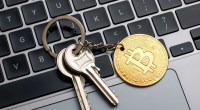 chaveiro com moeda de bitcoin em cima de teclado de laptop