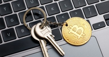 chaveiro com moeda de bitcoin em cima de teclado de laptop