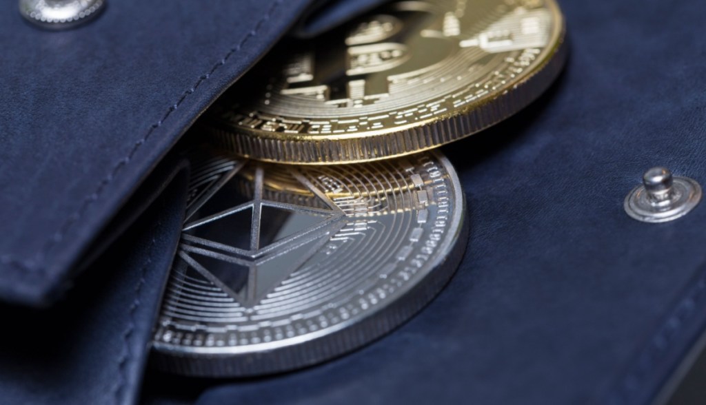 Moedas de Bitcoin e Ethereum à mostra em uma carteira de couro