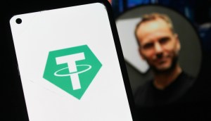 Logo da tether no celular, ao fundo busto de Paolo Ardoino desfocado