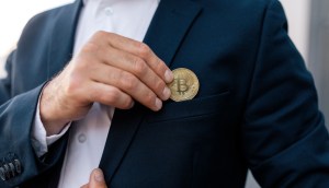 Homem de paletó tira moeda de Bitcoin do bolso