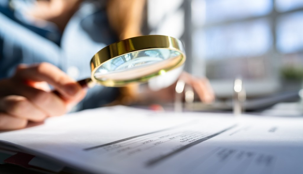pessoa usa lupa sobre documento