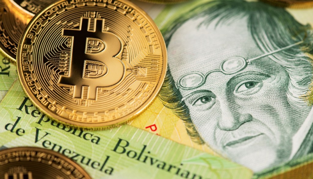 moeda de bitcoin junto a notas de bolivares, moeda da Venezuela